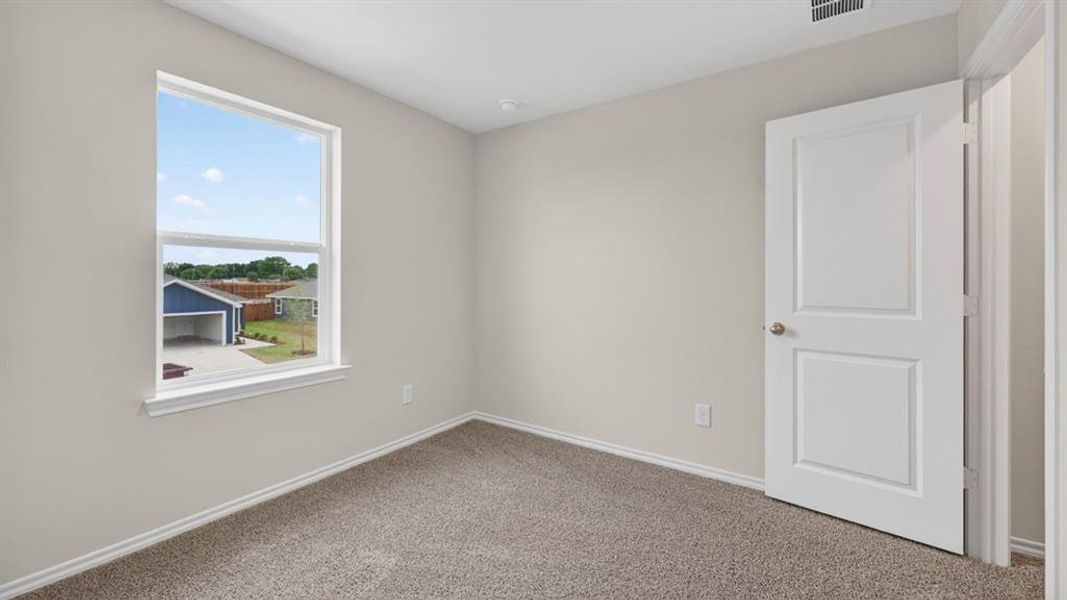 Neutral wall color, window with white trim, gray carpet, white baseboards, and a white paneled door