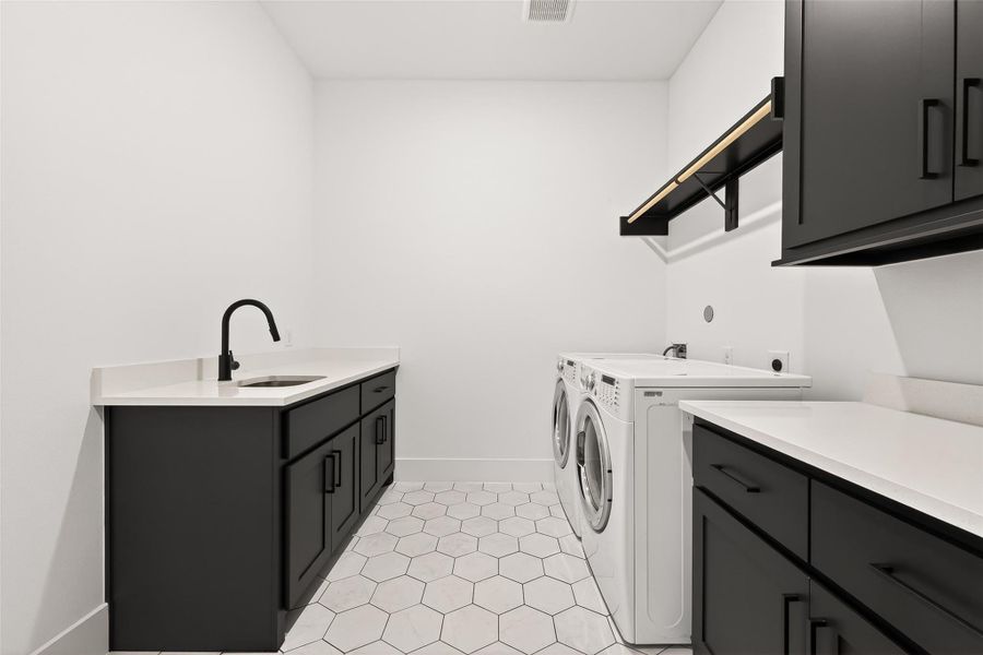 Additional first-floor amenities include a large utility room featuring designer hexagon tile flooring, sink, cabinetry, ample counter space, and hidden in-wall ironing board, plus a stylish powder bath nearby.