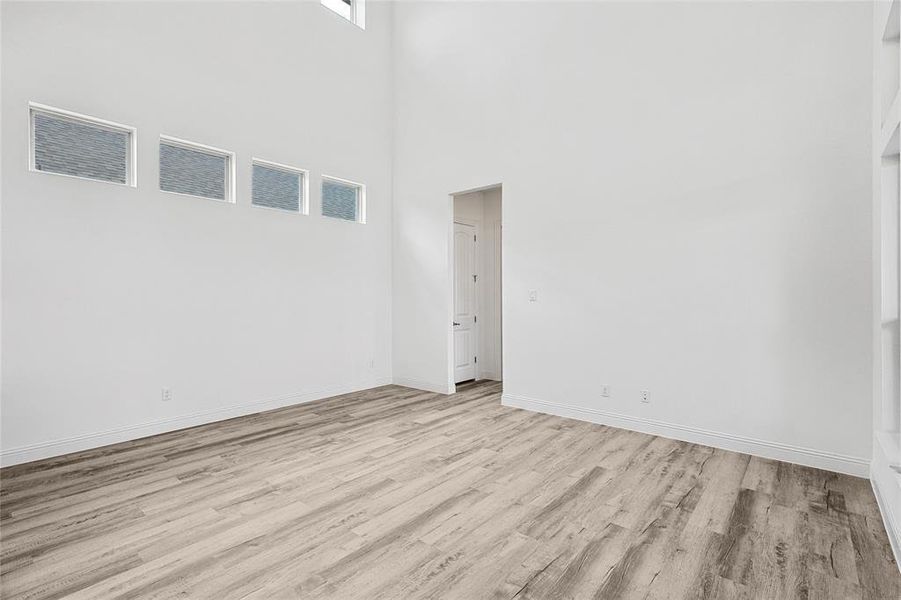 Unfurnished room featuring light hardwood / wood-style floors and a towering ceiling