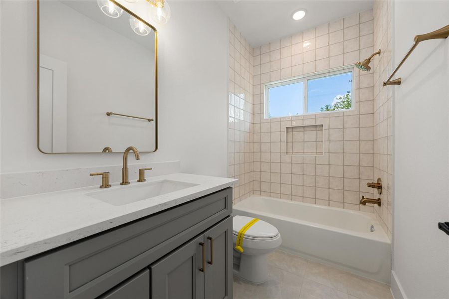 Secondary bath features tile flooring, bath/shower combo with tile surround, grey cabinets, beautiful light countertops, mirror, sleek fixtures and modern finishes. Secondary bath features tile flooring, bath/shower combo with tile surround, grey cabinets, beautiful light countertops, mirror, sleek fixtures and modern finishes.
