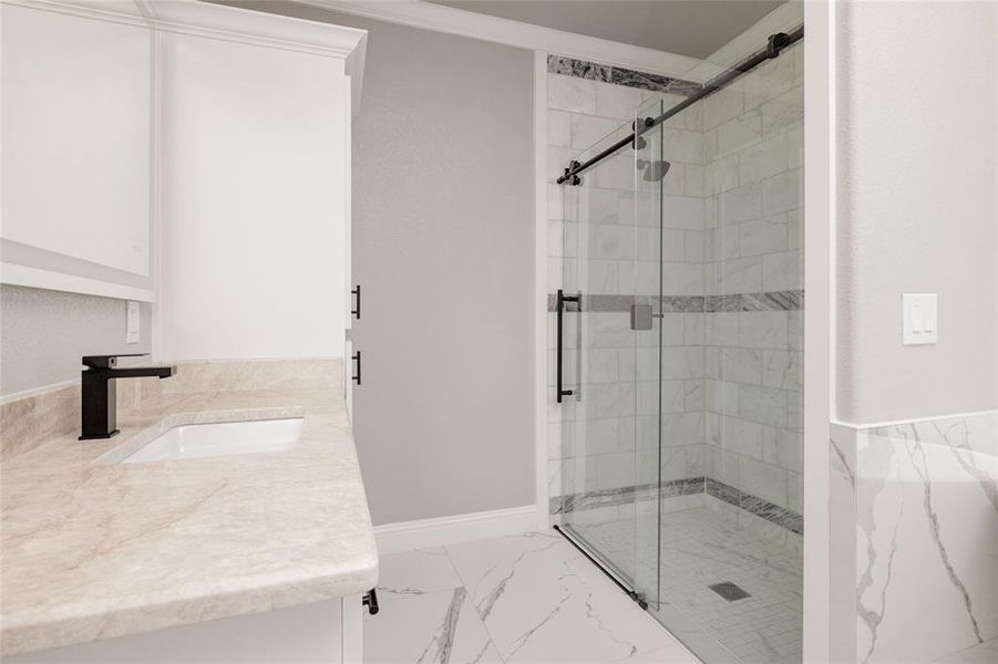 Bathroom featuring vanity, marble finish floor, a shower stall, and ornamental molding Bathroom featuring vanity, marble finish floor, a shower stall, and ornamental molding