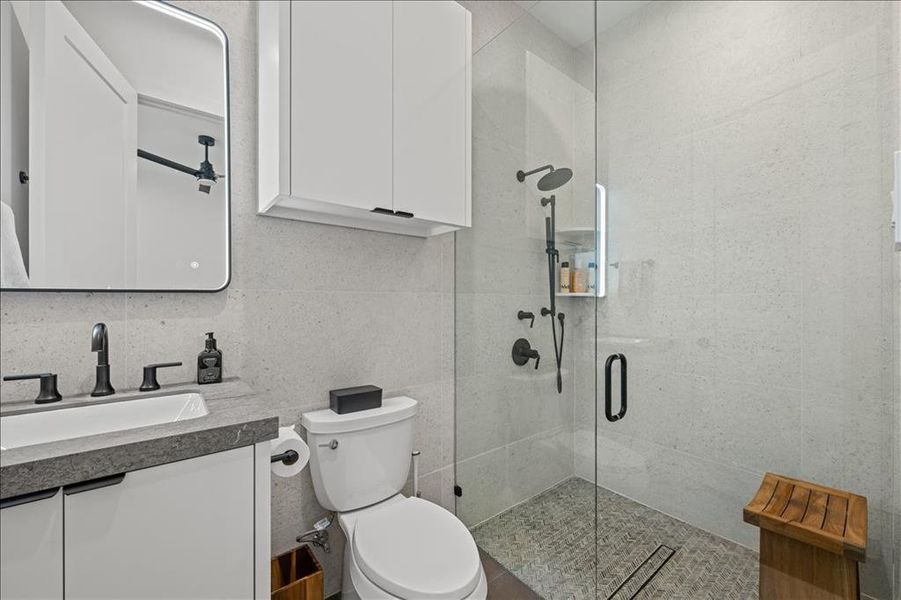 2nd primary full bath with vanity, a stall shower, tile walls, and backsplash
