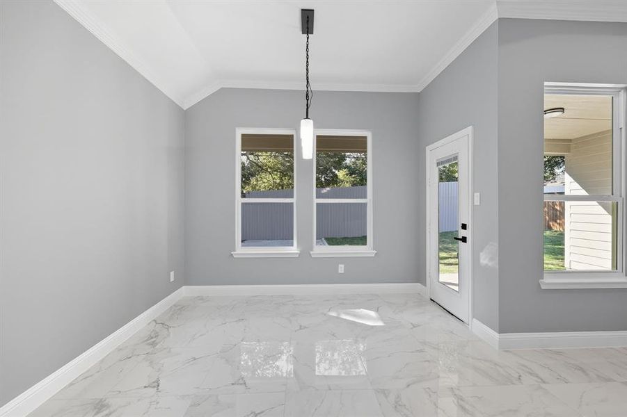 Unfurnished dining area featuring crown molding and light marble finish flooring Unfurnished dining area featuring crown molding and light marble finish flooring