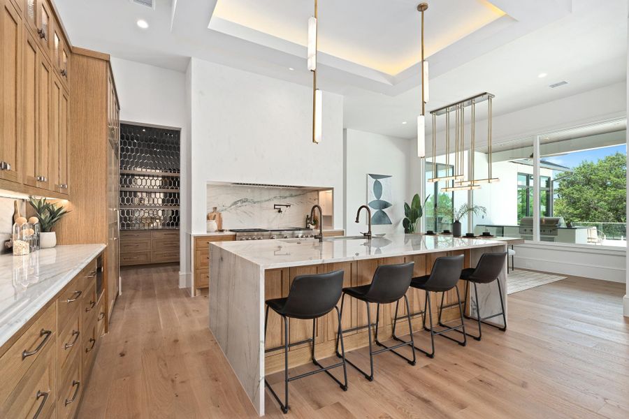 A well-lit, open-concept kitchen boasts a large island with seating and views of the outdoors.