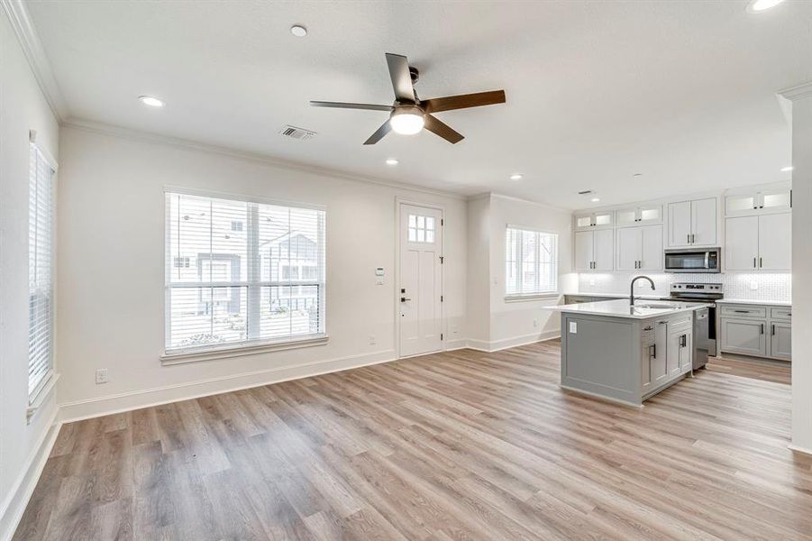 Kitchen featuring a sink, light wood finished floors, stainless steel appliances, ceiling fan, and ornamental molding Kitchen featuring a sink, light wood finished floors, stainless steel appliances, ceiling fan, and ornamental molding