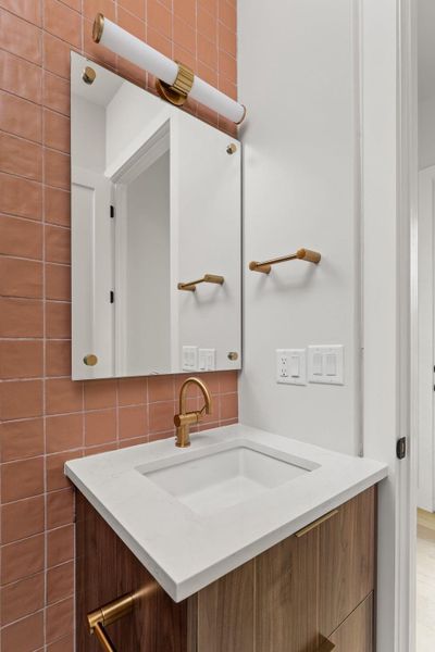 Bathroom featuring vanity, tile walls, and tasteful backsplash