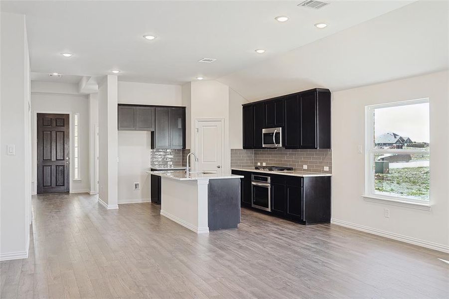 Kitchen featuring backsplash, a center island with sink, sink, light hardwood / wood-style flooring, and stainless steel appliances