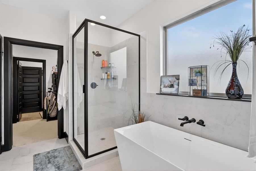 Freestanding soaking tub with wall-mounted matte black fixtures