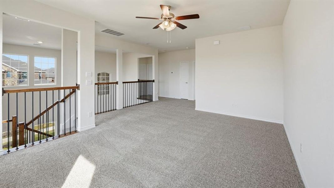 Carpeted spare room featuring a ceiling fan