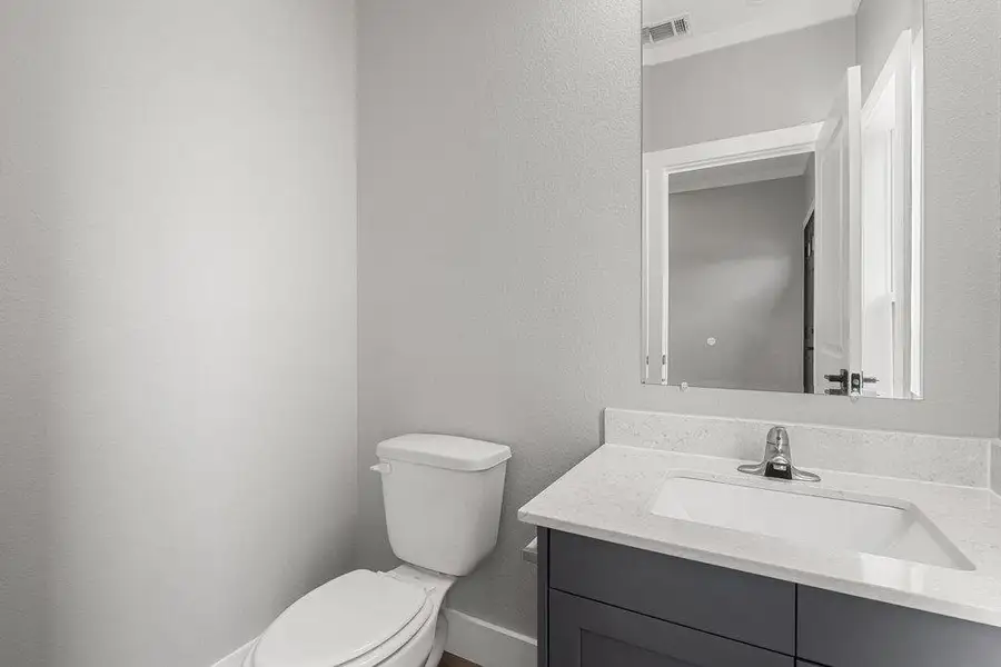 Half bathroom featuring vanity and a textured wall