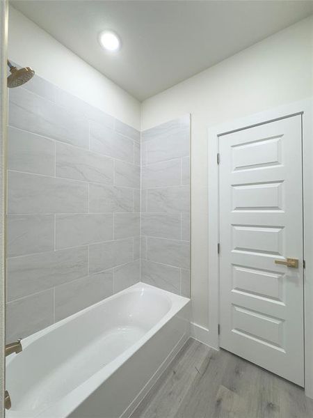 Bathroom featuring tiled shower / bath combo and hardwood / wood-style flooring