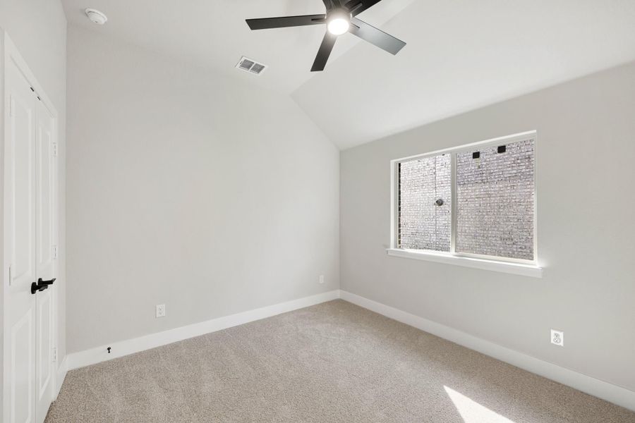 Empty bedroom with vaulted ceiling, black ceiling fan, carpet flooring, and single window