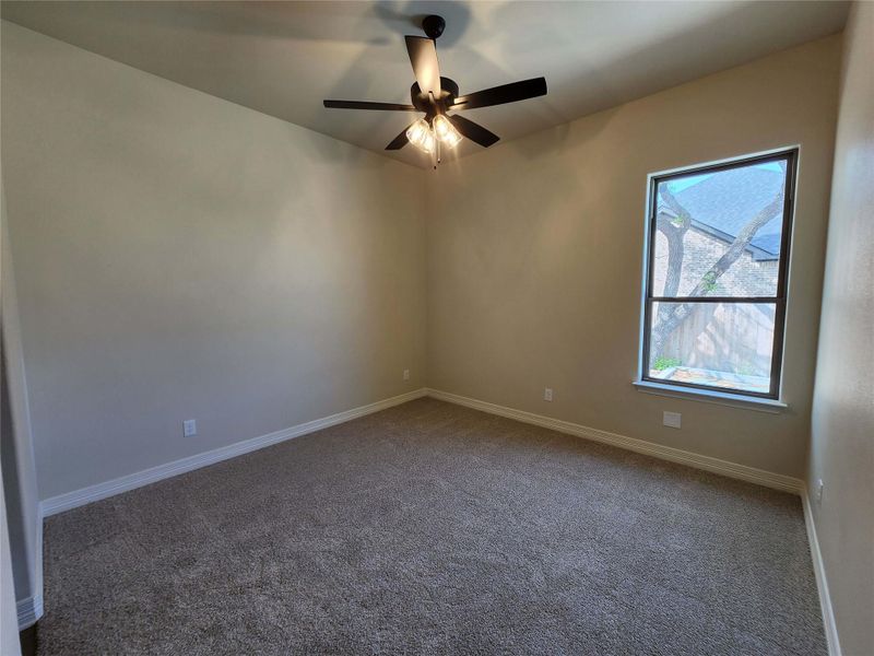 Unfurnished room with dark carpet and ceiling fan
