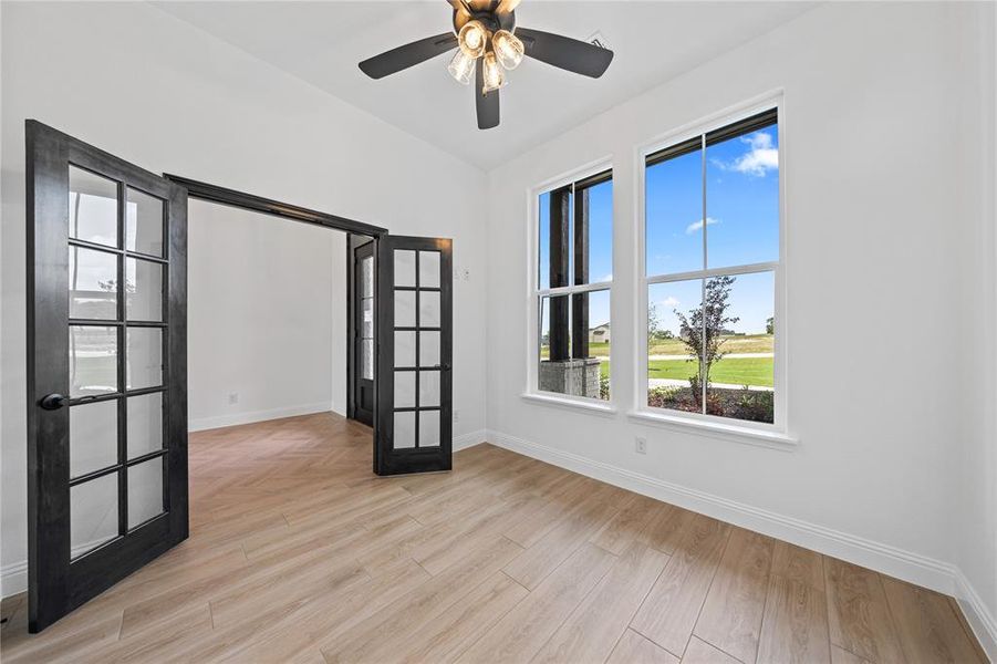Empty room with french doors, light wood-style floors, and a ceiling fan