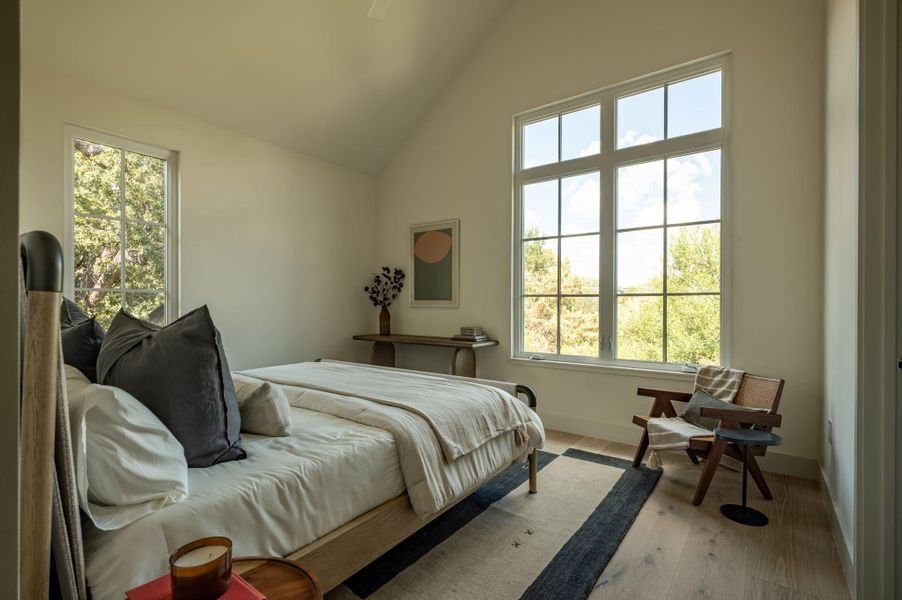 Vaulted ceilings and towering windows frame tranquil neighborhood views in this light-filled bedroom. Vaulted ceilings and towering windows frame tranquil neighborhood views in this light-filled bedroom.