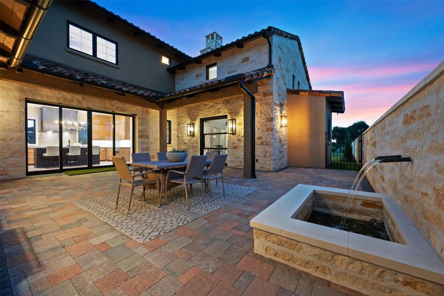 Lovely water feature and large, paved courtyard area. Beautiful stone & stucco exterior home with tile roof.