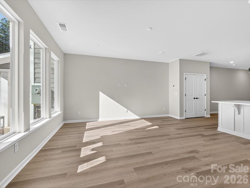 Light filled living room with picture windows allowing natural light to fill the space & views of the yard & woods