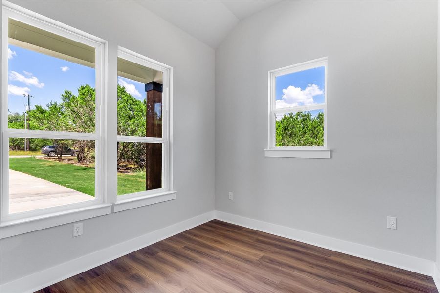 Empty room featuring dark wood finished floors and lofted ceiling