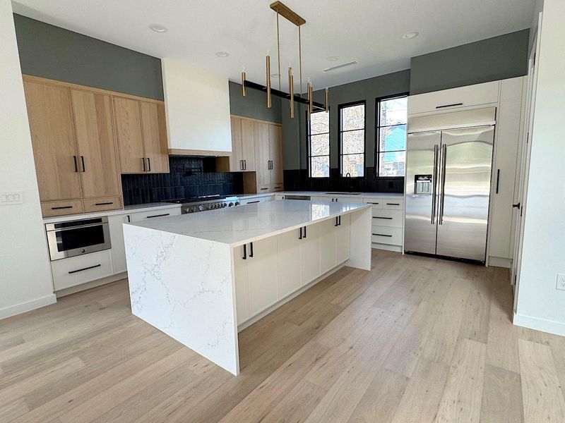 Kitchen with a center island, range hood, stainless steel appliances, and modern cabinets