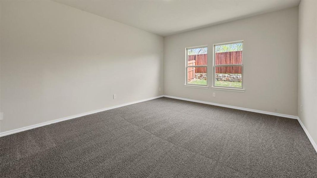Spacious room featuring neutral-toned walls, plush carpet flooring, and two large windows providing natural light