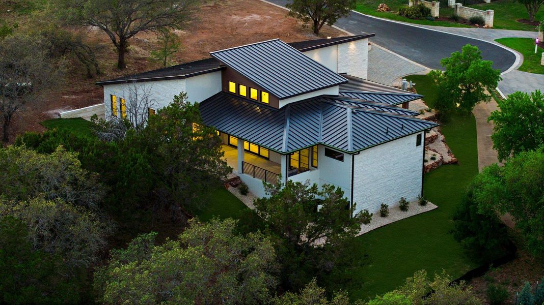 Modern architecture with a sleek dark roofline and luminous windows illuminates the surrounding landscape.