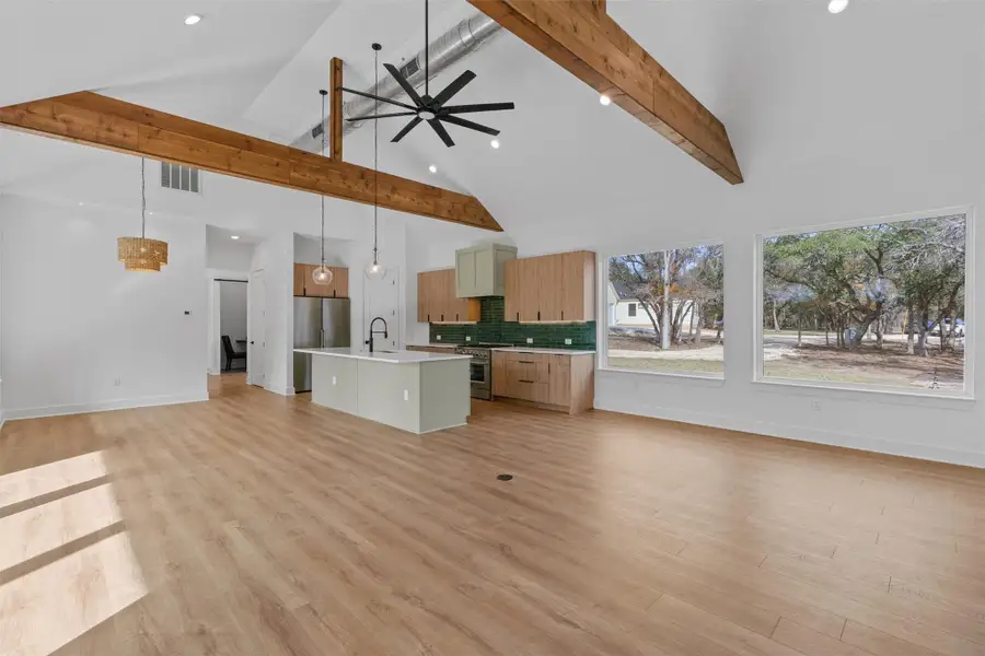 A spacious, naturally illuminated kitchen and living area, complete with an inviting island and expansive windows. A spacious, naturally illuminated kitchen and living area, complete with an inviting island and expansive windows.