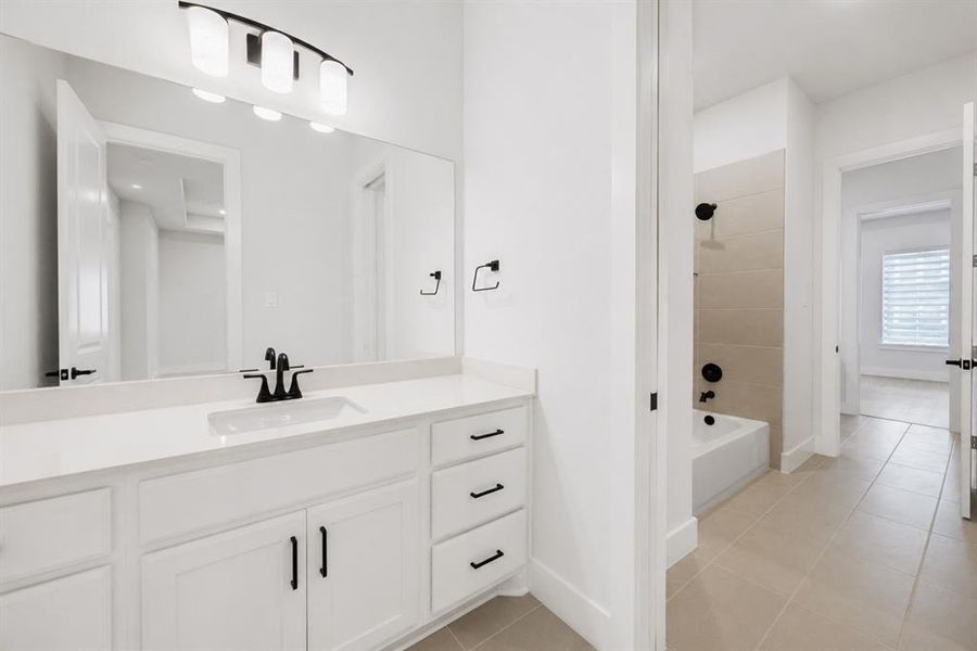 Bathroom featuring a white vanity with an integrated sink, quartz countertop, and matte black fixtures
