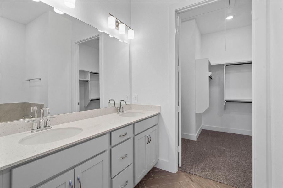 This stunningly updated primary bathroom is truly move-in ready! It features stained cabinetry with light countertops, dual vanities, a large mirror, high ceilings, custom paint, and sleek modern finishes throughout.
