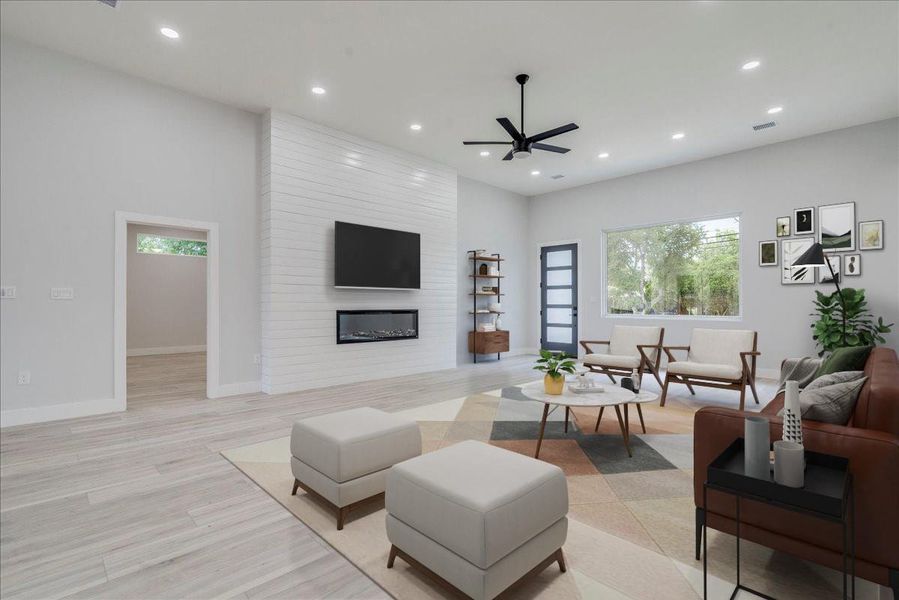 Living room featuring recessed lighting, ceiling fan, light wood finished floors, and a large fireplace Living room featuring recessed lighting, ceiling fan, light wood finished floors, and a large fireplace