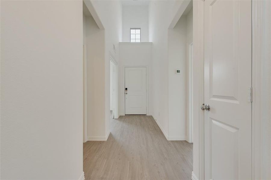 Hall with a high ceiling and light hardwood / wood-style flooring