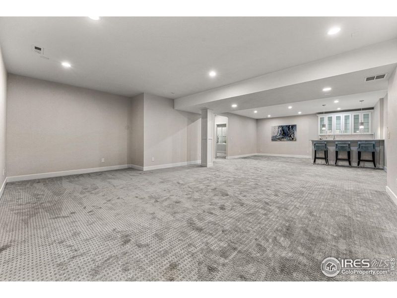 Spacious basement entertainment space with wet bar.