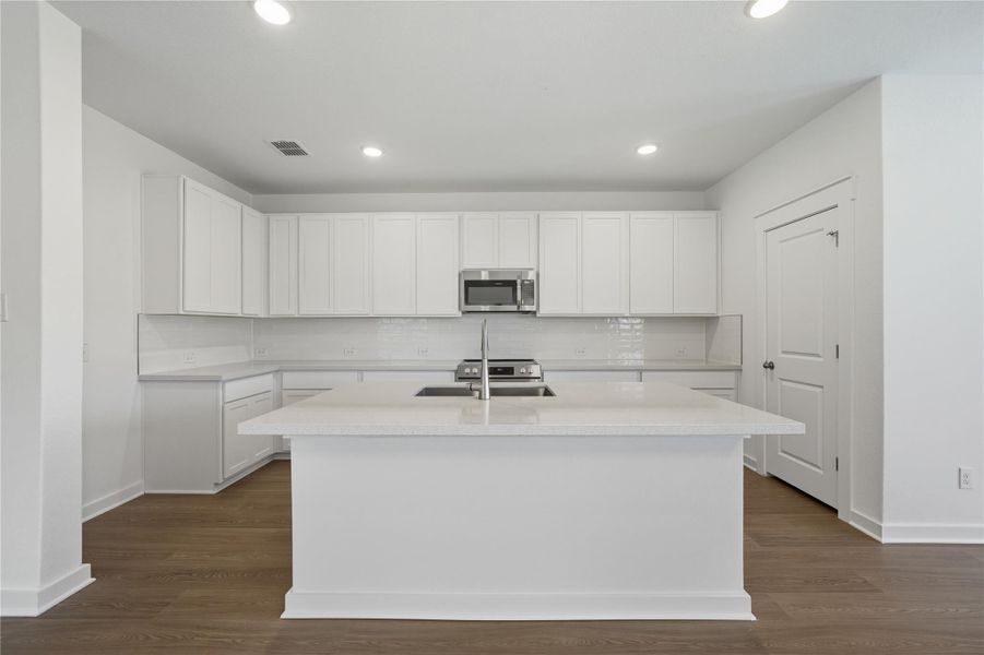 Kitchen with white cabinetry, backsplash, light stone countertops, stainless steel appliances, and recessed lighting Kitchen with white cabinetry, backsplash, light stone countertops, stainless steel appliances, and recessed lighting