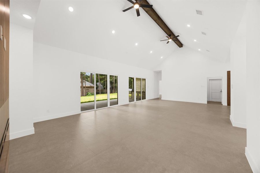 Spacious living area featuring vaulted ceilings, exposed beam accents, and multiple sliding glass doors.