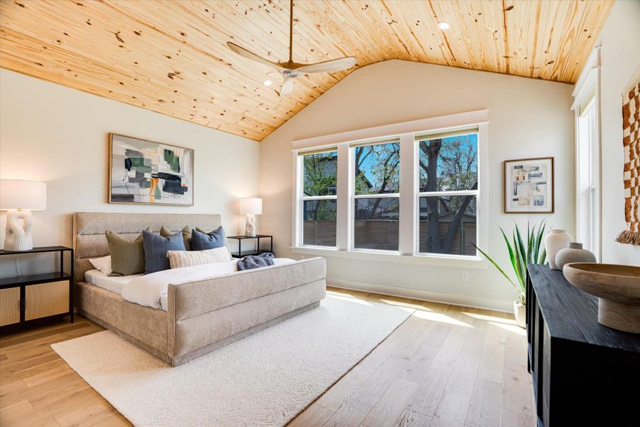 This property features a vaulted ceiling with wood paneling and a ceiling fan, light wood flooring, and large windows providing natural light This property features a vaulted ceiling with wood paneling and a ceiling fan, light wood flooring, and large windows providing natural light