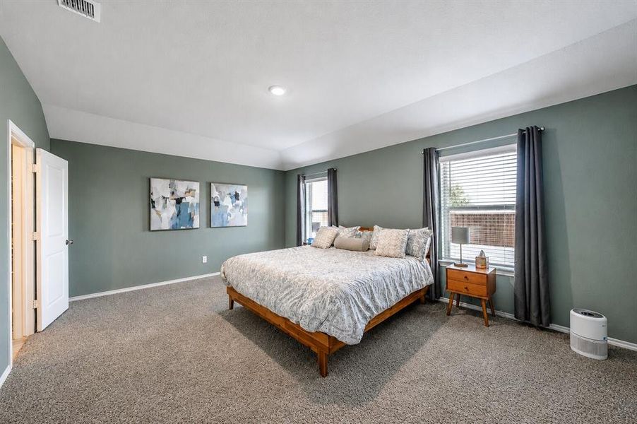Spacious room featuring carpeting, tray ceiling, recessed lighting, and two windows with blinds and drapes