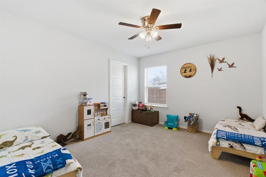 Carpeted bedroom with ceiling fan and baseboards