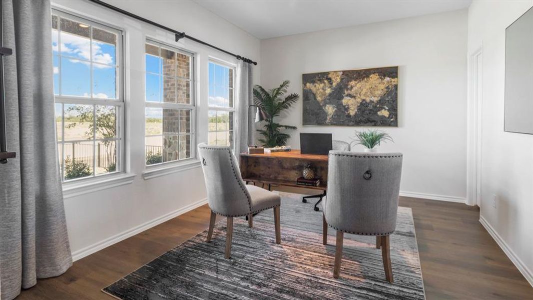 Bright interior space featuring three large windows with grid accents, wood-finish flooring, and crisp white walls