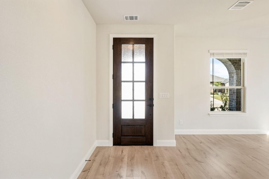 Entryway with dark wood front door featuring glass panels and light hardwood floors