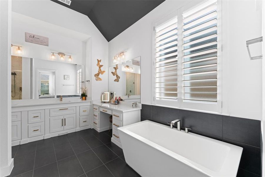 Full bath featuring a soaking tub, dark tile patterned floors, vanity, lofted ceiling, and a shower stall Full bath featuring a soaking tub, dark tile patterned floors, vanity, lofted ceiling, and a shower stall