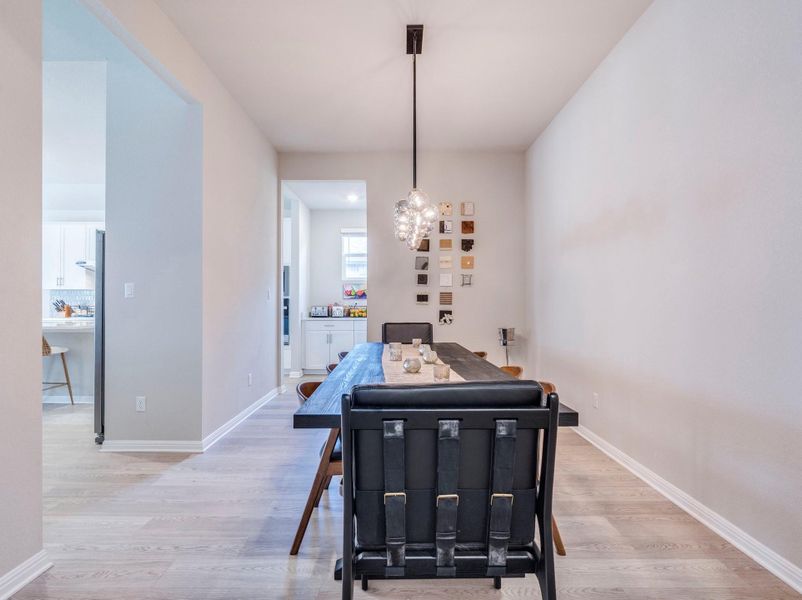 A contemporary chandelier illuminates the lengthy dining space, showcasing light hardwood floors. Easy to change fixture.