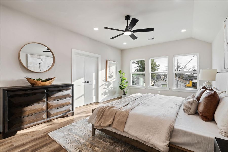 This serene bedroom offers a bright, spacious atmosphere with an elevated ceiling and wide windows that frame the neighborhood view. It’s a relaxing escape designed to feel comfortable, open, and effortlessly welcoming.