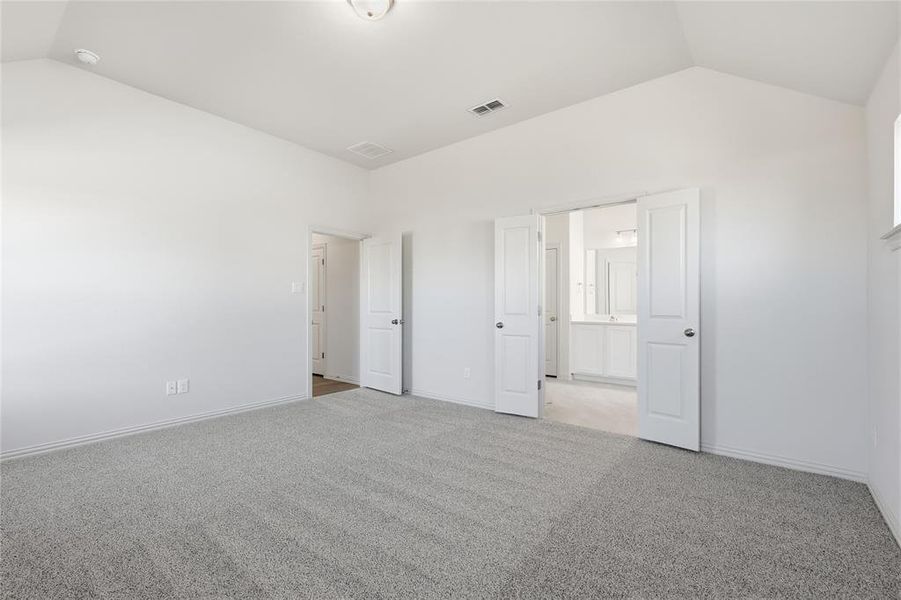 Unfurnished bedroom with vaulted ceiling and light colored carpet