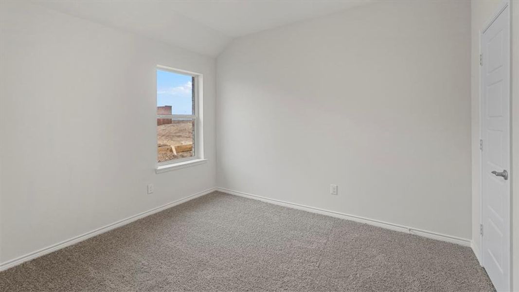 Light-filled interior space featuring a single window, neutral wall paint, gray carpeting, white baseboards, and a white interior door with panel detailing