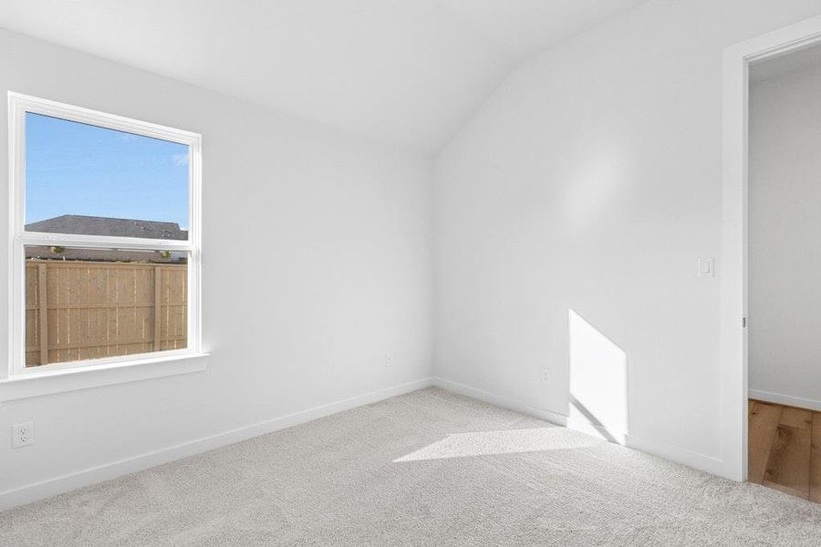 Unfurnished room with vaulted ceiling and carpet flooring