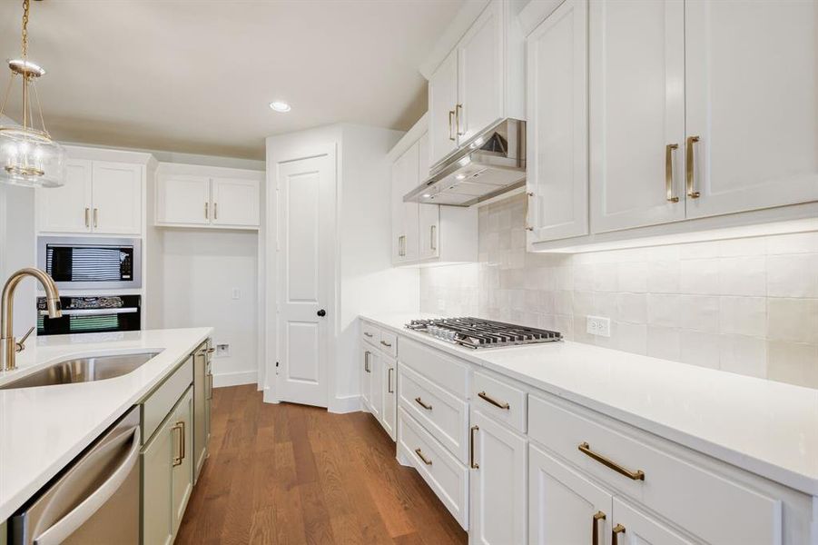 Gourmet kitchen featuring white shaker cabinetry, stainless steel appliances, a gas cooktop, white countertops, and wood-finish flooring