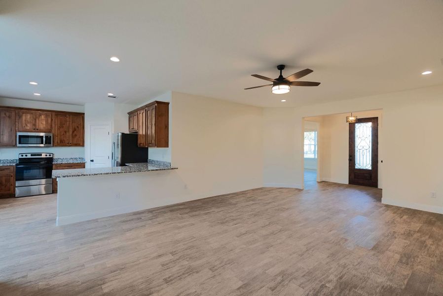 Kitchen with recessed lighting, appliances with stainless steel finishes, open floor plan, light stone counters, and light wood finished floors Kitchen with recessed lighting, appliances with stainless steel finishes, open floor plan, light stone counters, and light wood finished floors