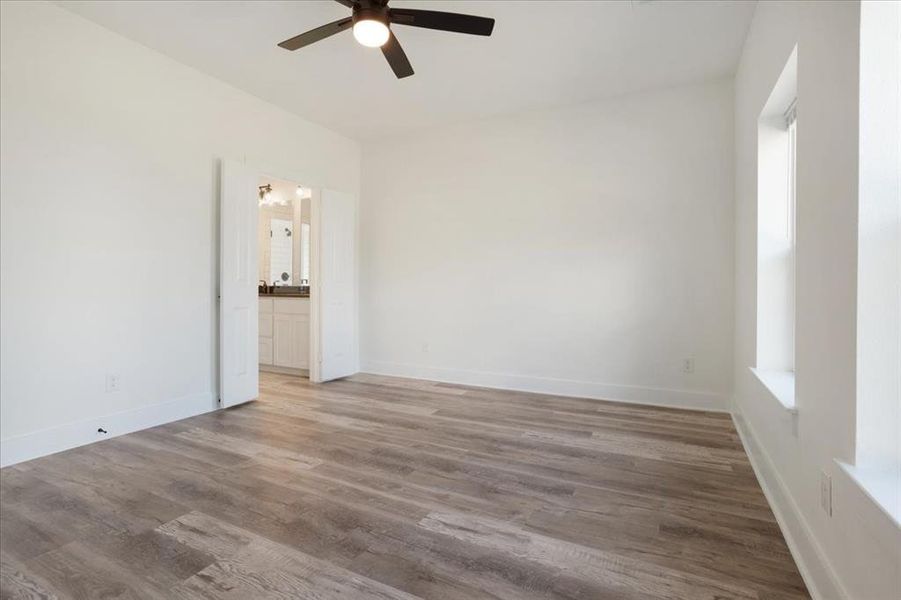 Master bedroom featuring wood-style floors, ceiling fan, and connected bathroom