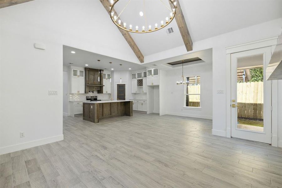 Unfurnished living room with sink, lofted ceiling with beams, and light wood-type flooring