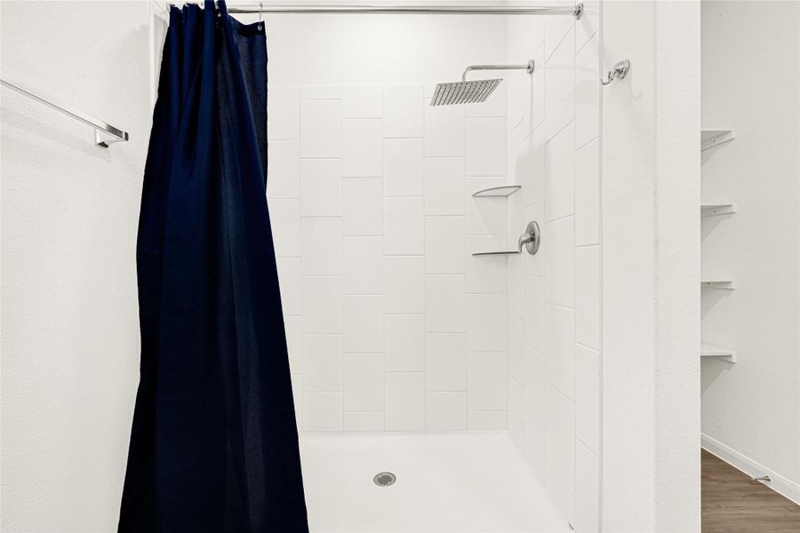 Clean and bright full bathroom featuring a tub/shower combo with a classic dark shower curtain.