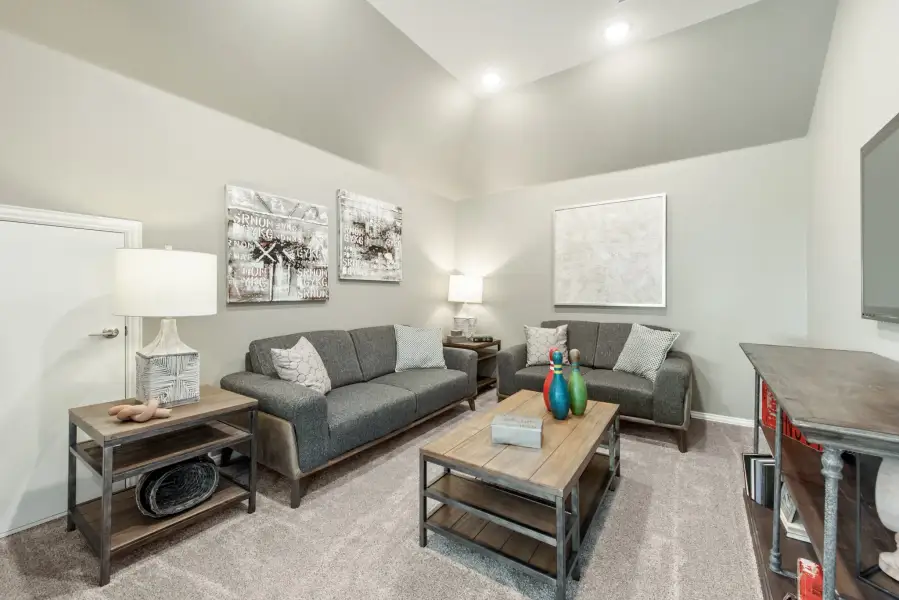 Living room with two gray sofas, wood coffee table, and vaulted ceiling with recessed lighting